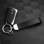 Clé de voiture noire posée sur une surface texturée, attachée à un porte-clés en cuir noir avec anneau métallique argenté