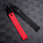 Deux porte-clés en tissu noir et rouge avec mousqueton métallique, posés sur fond noir texturé