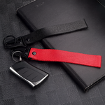 Porte-clés en tissu noir et rouge avec mousqueton, sans logo, posé sur fond texturé