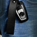 Porte-clés en tissu noir accroché à une clé de voiture, fixé à un jean