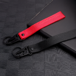 Deux porte-clés en tissu rouge et noir avec mousquetons, posés sur une surface sombre texturée