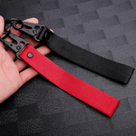 Deux porte-clés en tissu noir et rouge avec mousqueton, présentés dans une main
