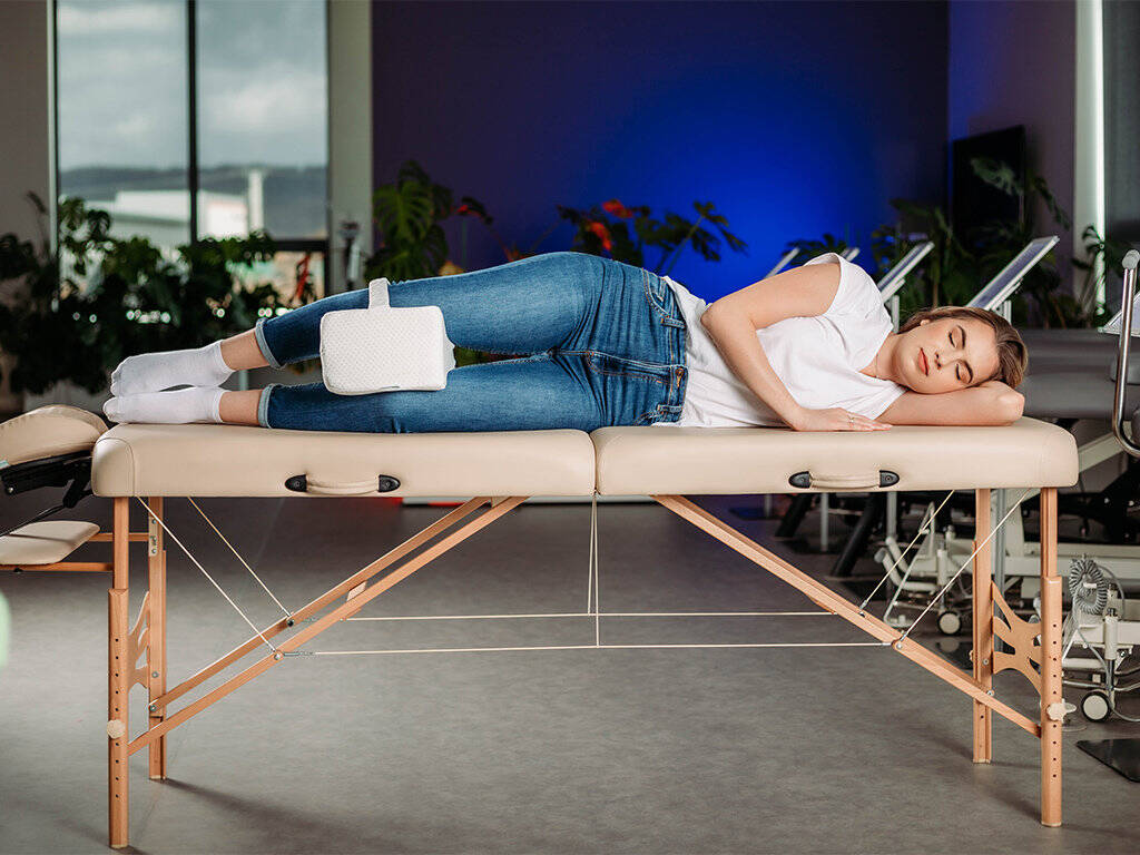 tablelya coussin genoux orthopédique avec sangle de fixation habys damart femme allongée sur une table de massage sur le coté