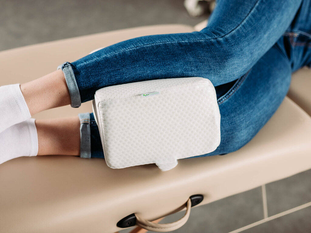 tablelya coussin genoux orthopédique avec sangle de fixation habys damart en position sur les jambes dune femme allongée sur le coté