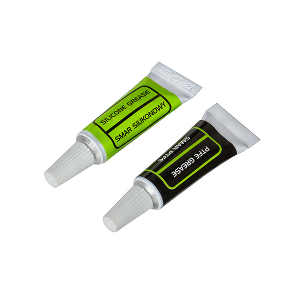 Deux petits tubes de graisse posés en biais : silicone à étiquette verte et PTFE à étiquette noire