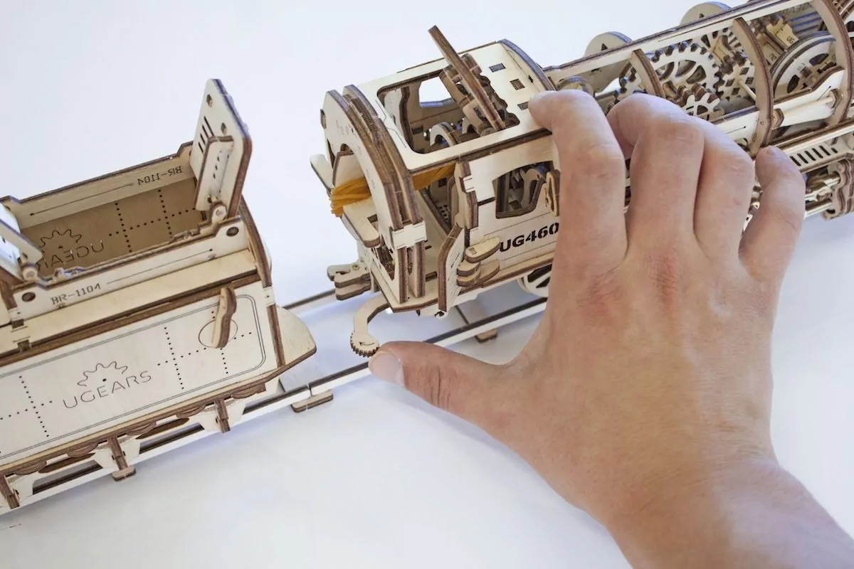 une main qui assemble un train à vapeur en 3d