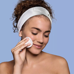 femme qui nettoie son visage avec un coton