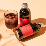 un verre remplie de Cola bio et deux de ses bouteilles