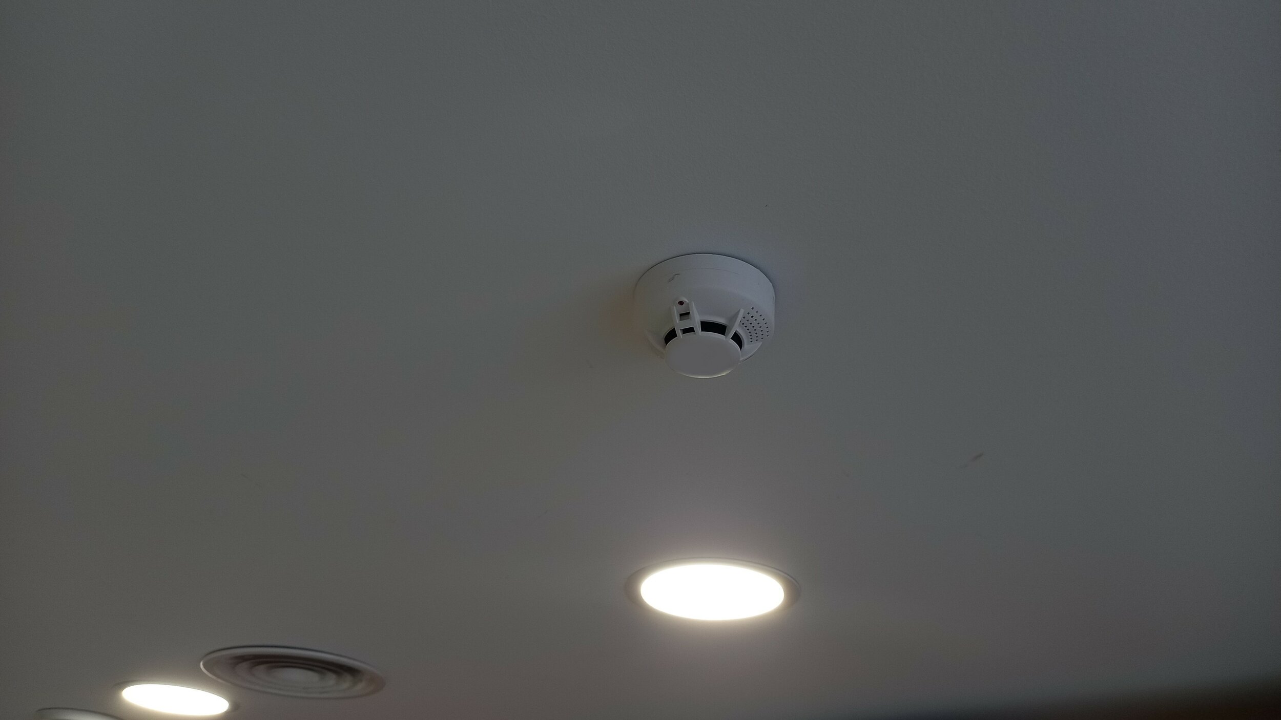 Détecteur de fumée blanc installé au plafond, microphone espion dissimulé