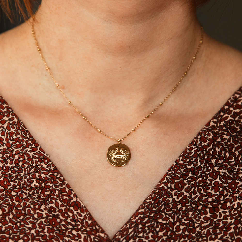 collier pendentif medaille frappee avec un crabe symbolisant le signe astrologique cancer porte