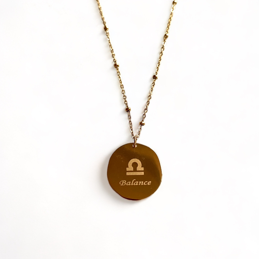 collier medaillon lisse au dos avec le signe astrologique balance ecrit mis en valeur sur fond blanc