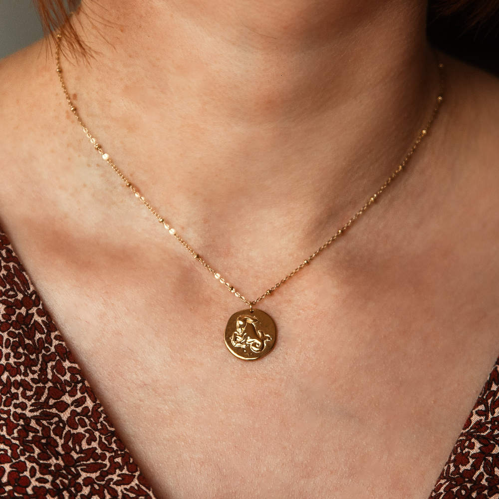 collier pendentif medaillon relief avec animal representant le signe astrologique capricorne porte