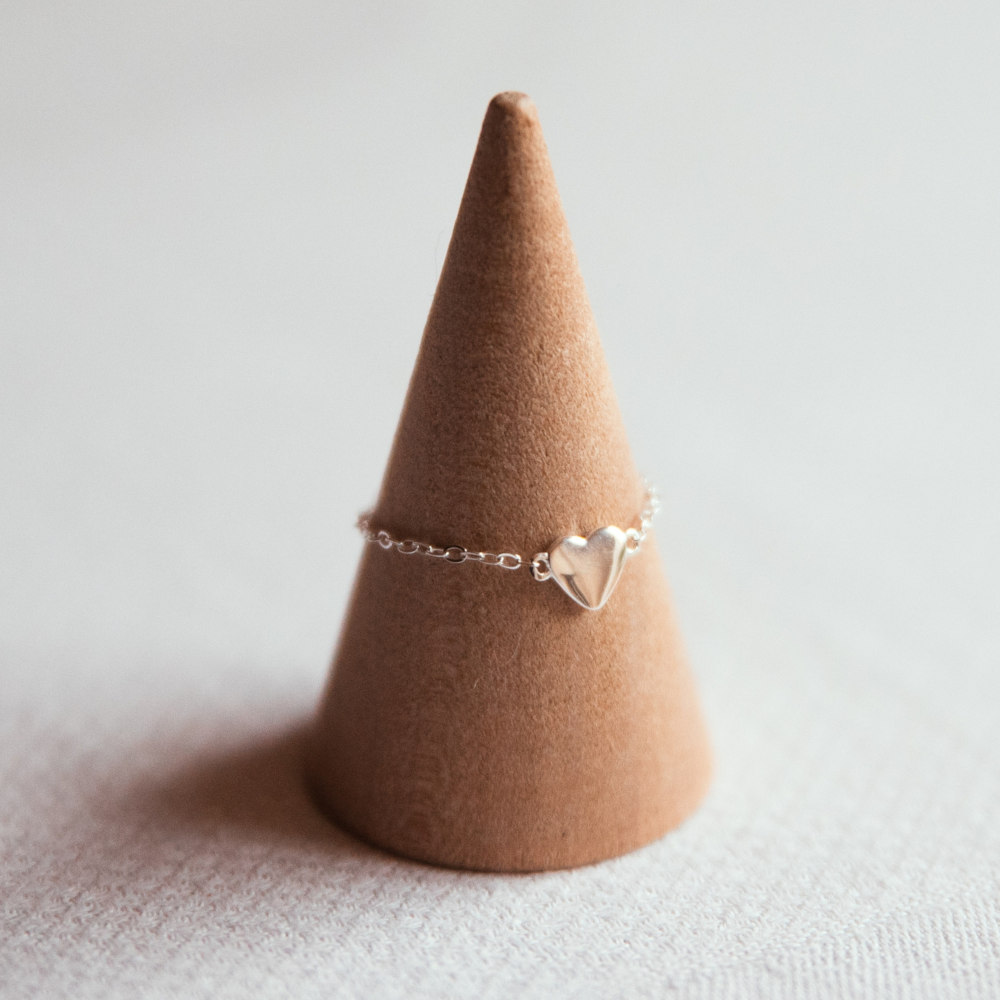 bague chainette argent avec petit coeur exposee sur cone en bois scarlett