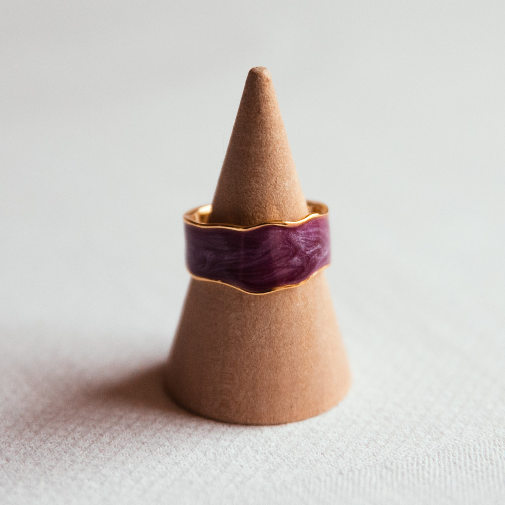 bague resine ajustable de couleur violette avec bords dores exposee sur cone en bois jade