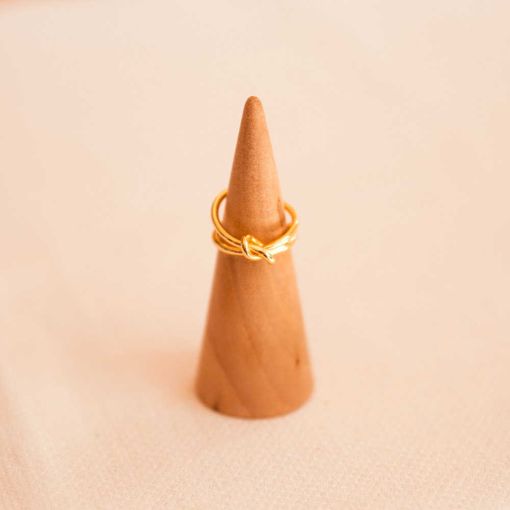 bague noeud double doree ouverte exposee sur cone en bois maelys