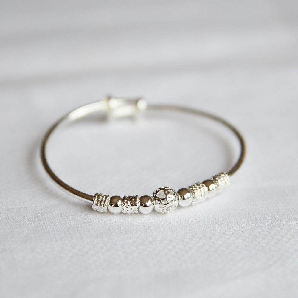 bracelet fantaisie modele avec perles dont une grande au milieu gravee avec coeurs expose fond blanc clea