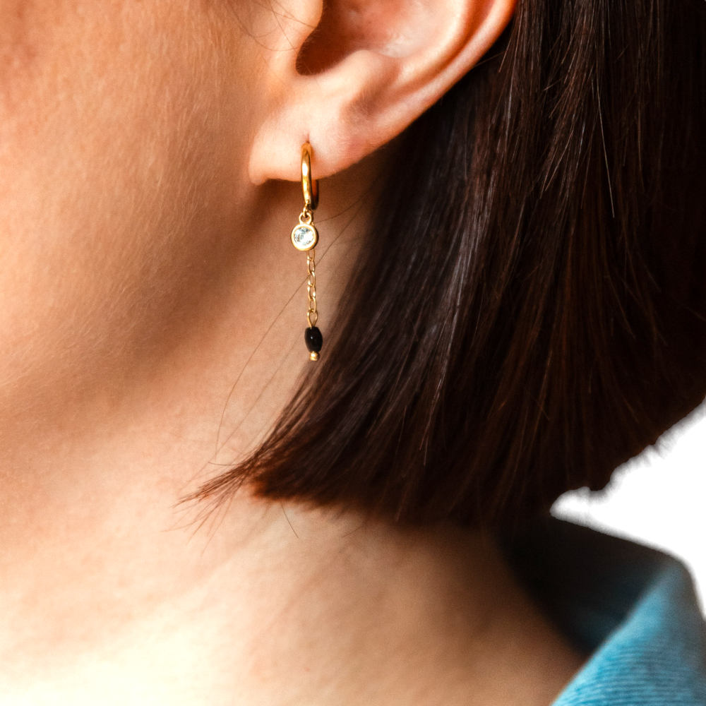 petites creoles dorees deux pendentifs strass et chainette avec une pierre noire portee oreille gauche tara