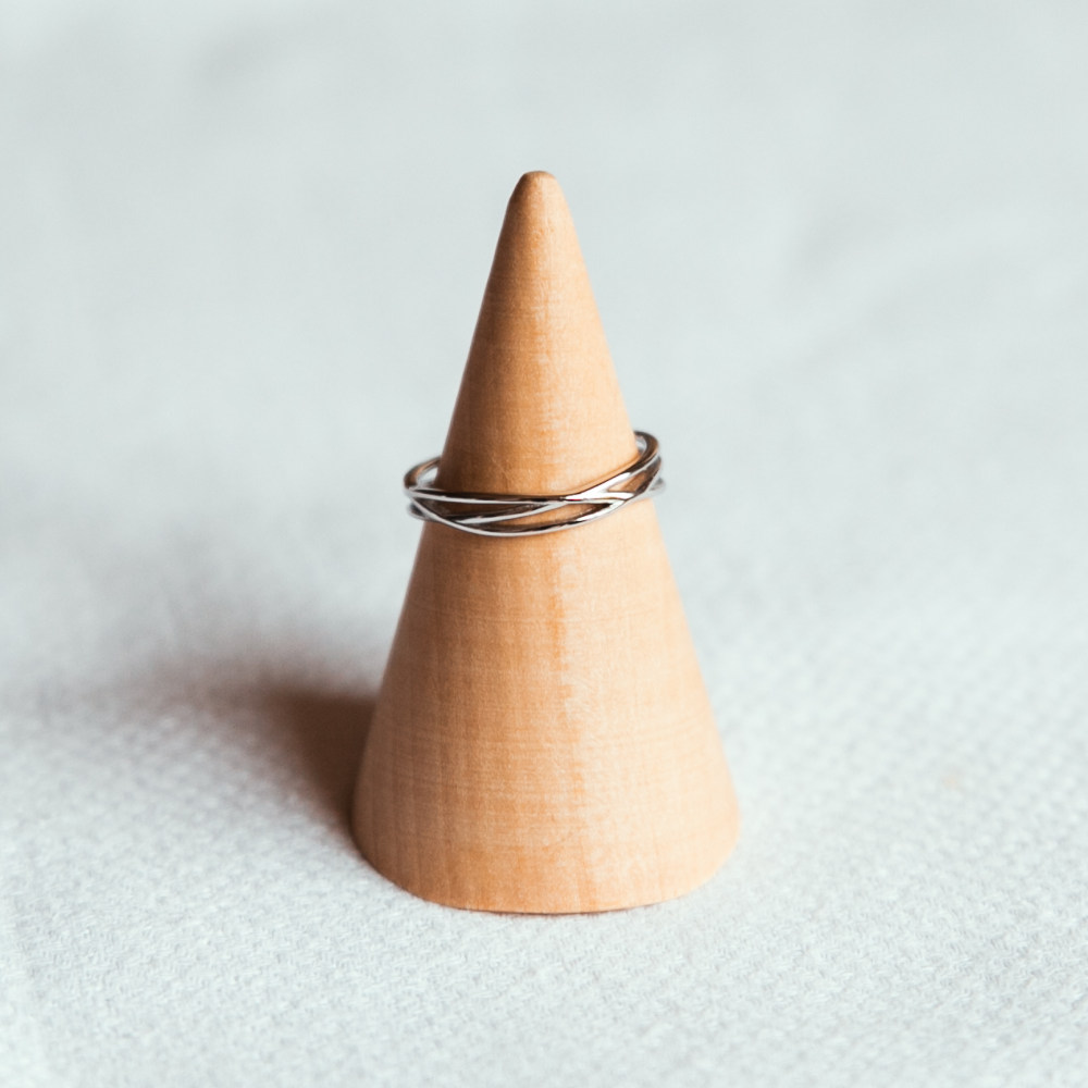 bague croisee en argent effet anneaux entrelaces exposee sur cone en bois elia