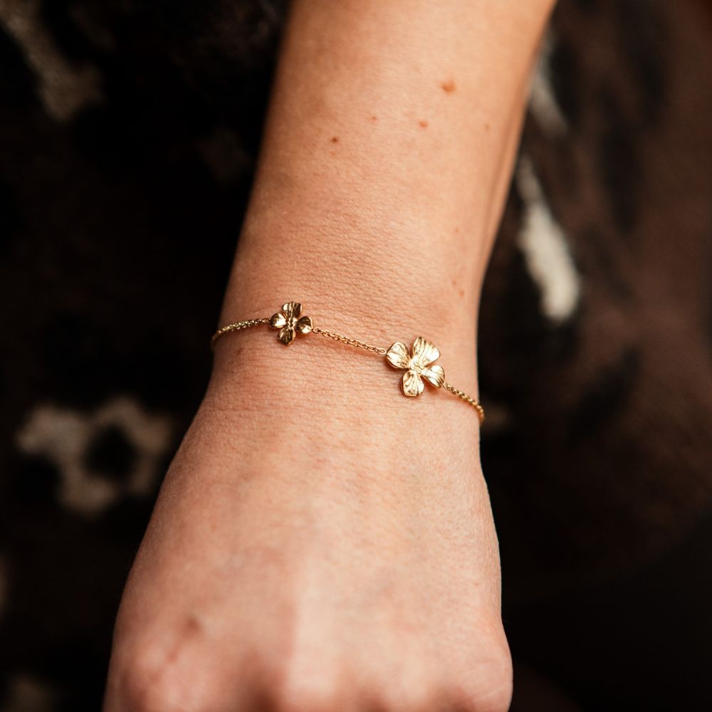 bracelet fleurs acier dore avec chaine ornee de deux fleurs texturees et porte sur bras gauche a la verticale heloise