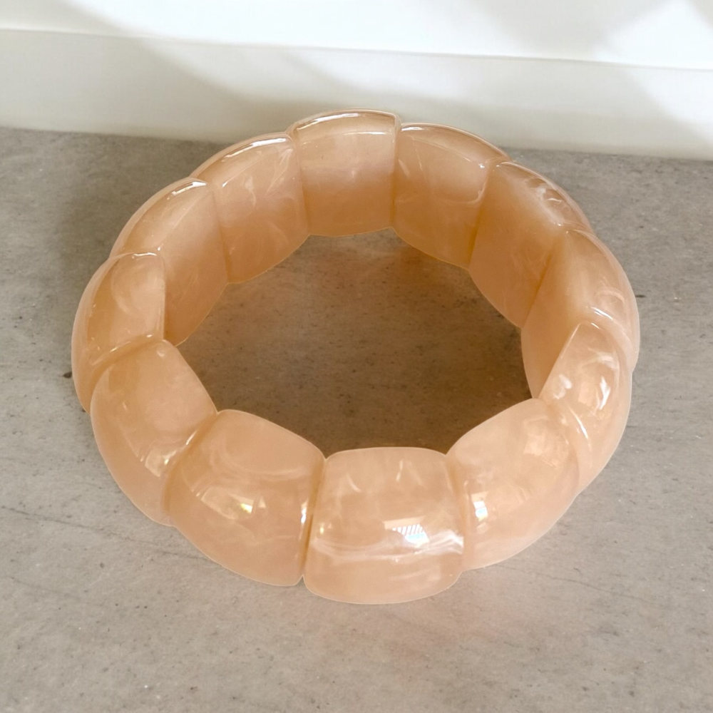 bracelet grosses perles roses avec reflets delicats et de forme manchette mis en valeur sur fond en beton lyra