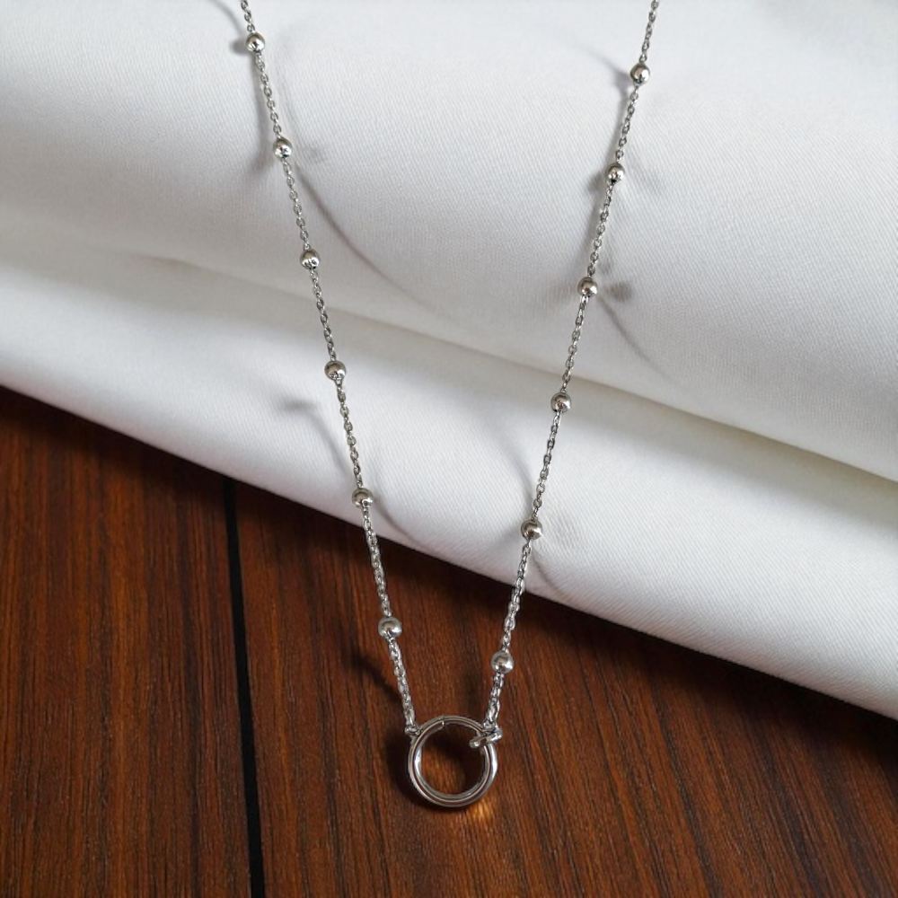 collier pour charms en acier inoxydable fermoir anneau en pendentif pour accrocher des petites breloques pose sur fond blanc et bois lia