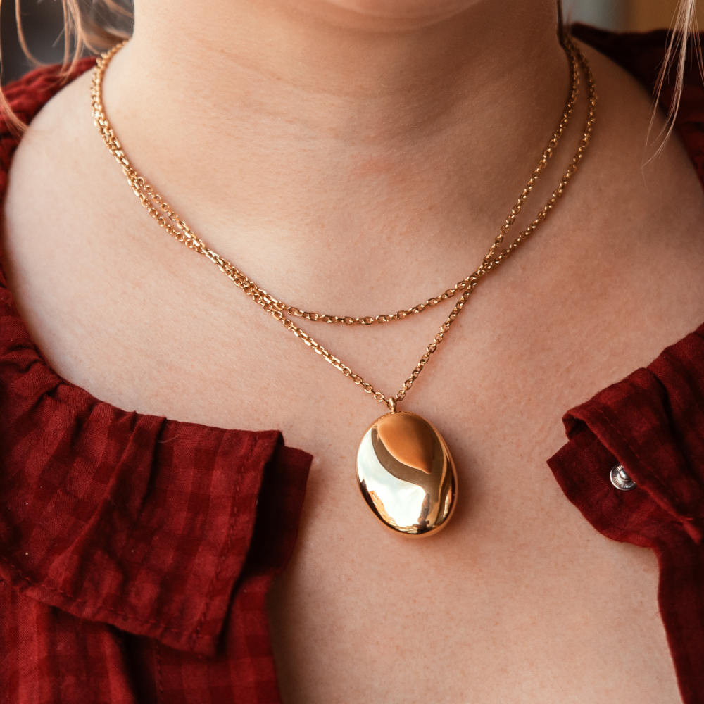 collier long sautoir dore avec son gros pendentif lisse bombe et lumineux porte enroule autour du cou florence
