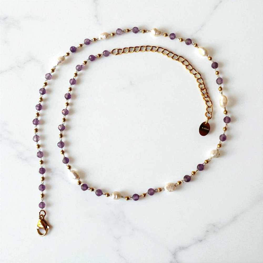 collier pierre amethyste lumineux en acier dore avec differentes perles alternees sur chaine et mis en valeur fond blanc jaia