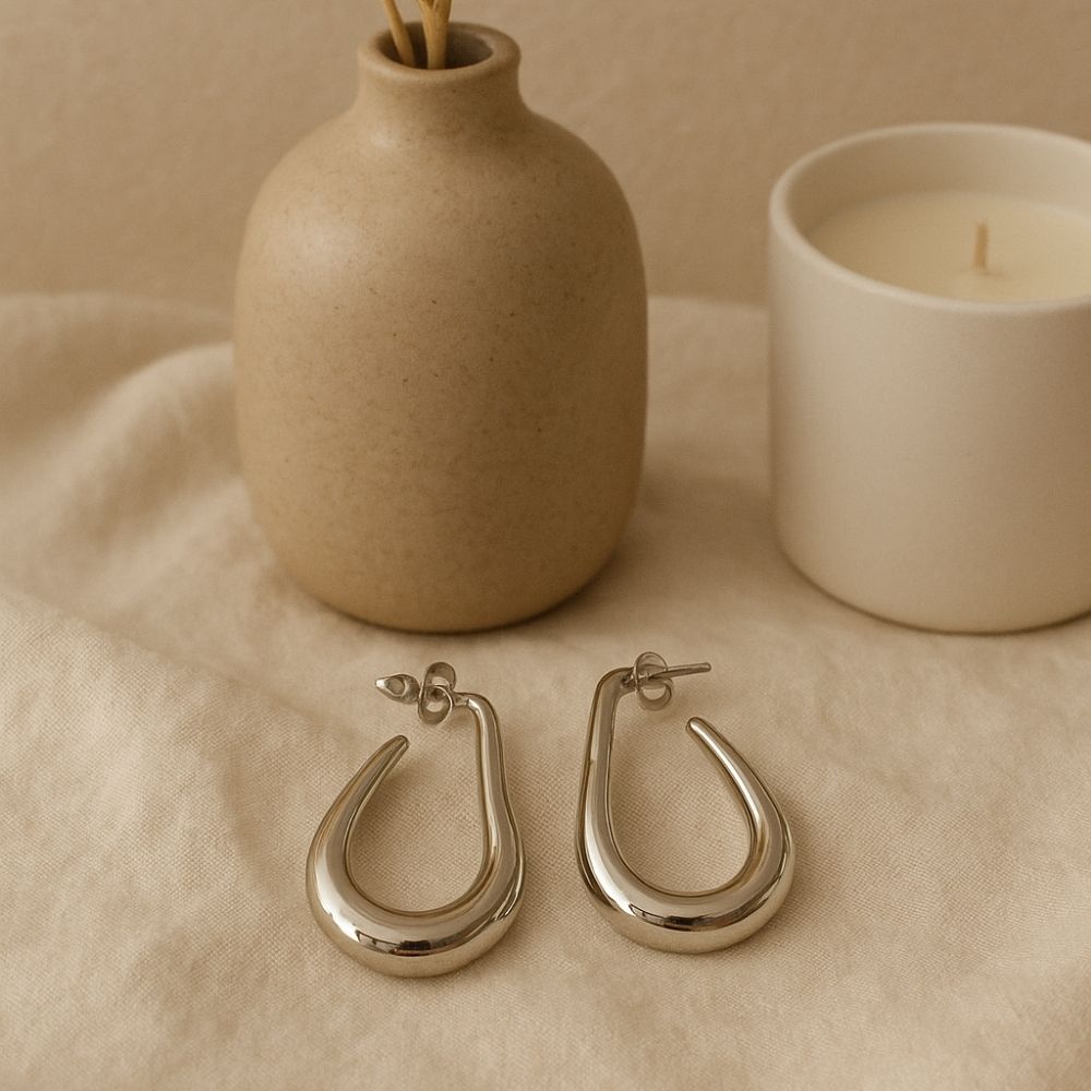 creoles argentees au design forme goutte epure et moderne en acier mises en valeur avec fond neutre decoratif anna