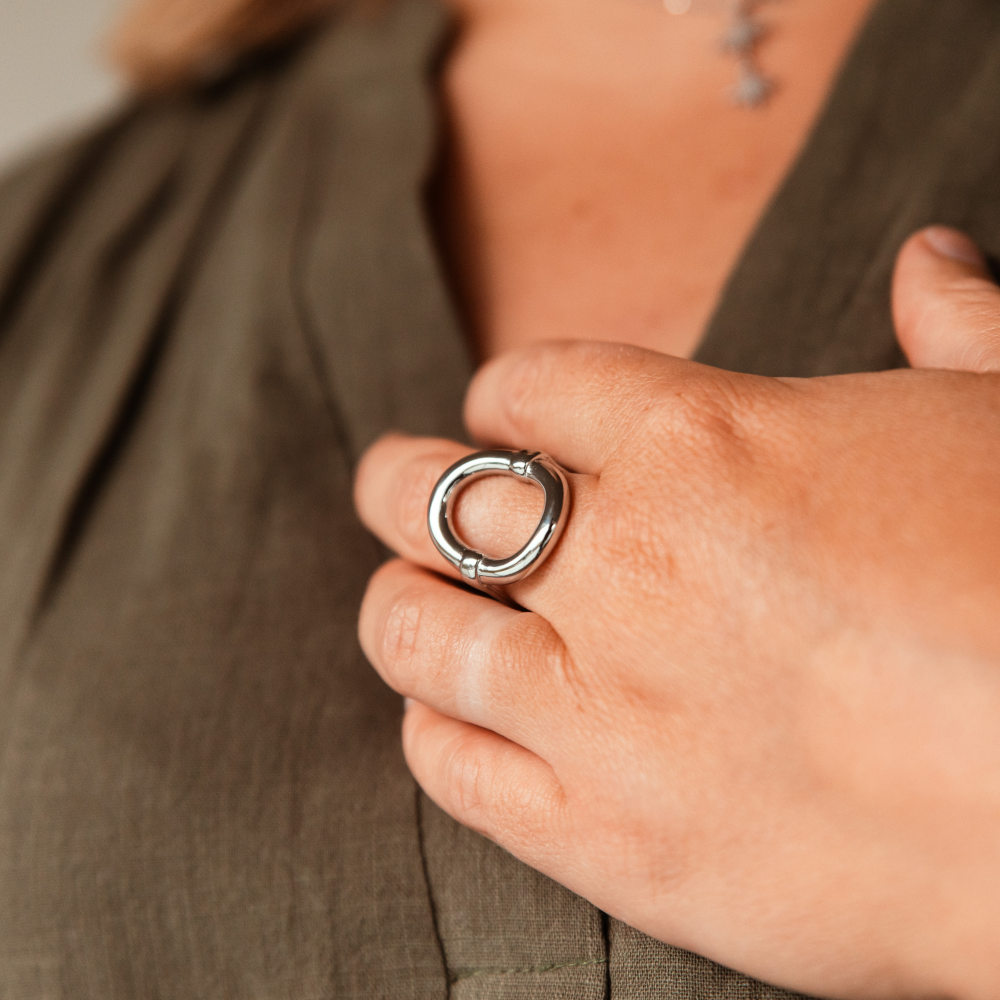 bague epaisse ovale berenice argentee avec grand anneau portee sur le majeur gauche main posee sur la poitrine