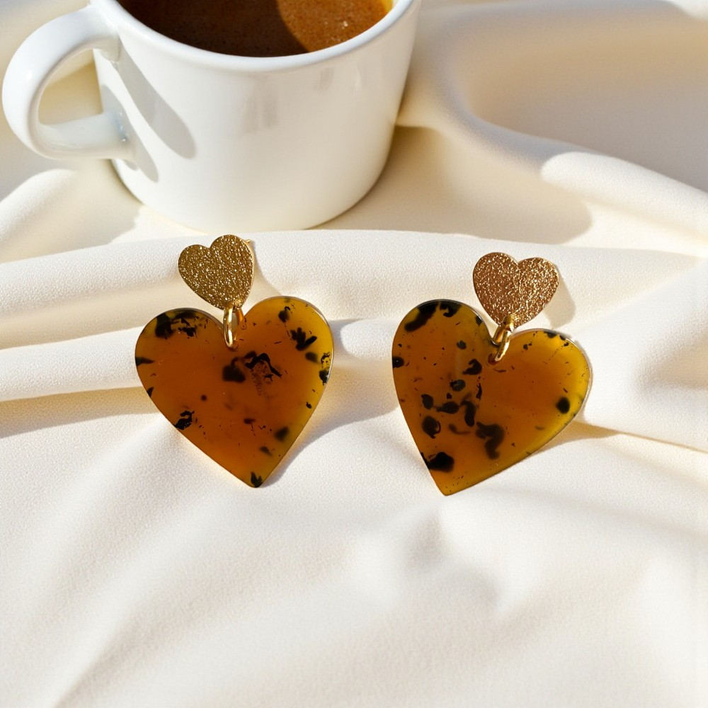 boucles d oreilles ecaille double coeur dore paillettes et grand coeur marron exposees sur fond de tissu beige miranda