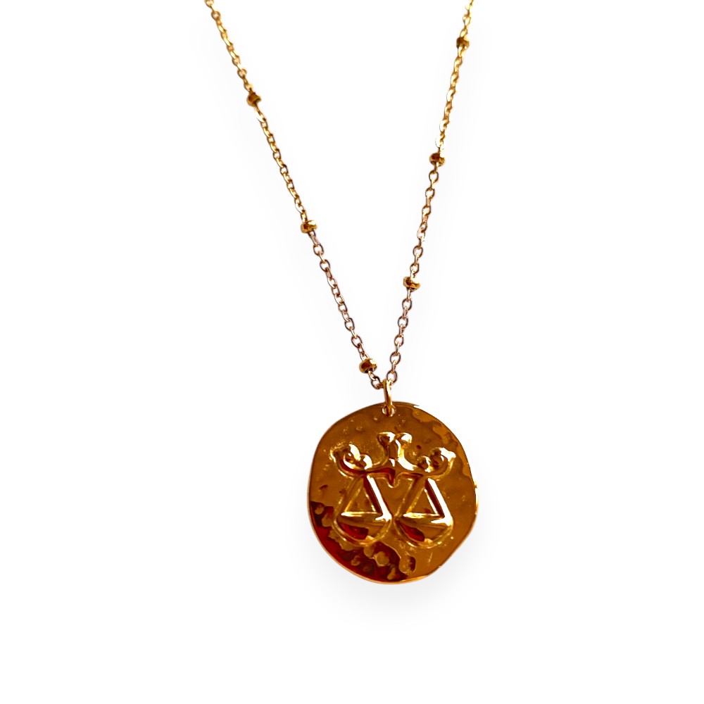 collier avec medaille frappee avec une balance symbolisant le signe astrologique expose fond blanc