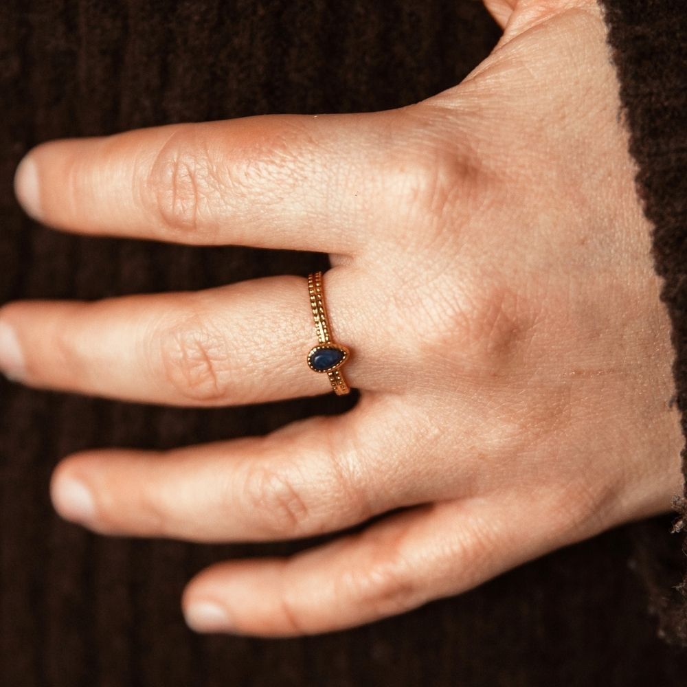 bague pierre bleue goutte dorée portée main pull marron acier inoxydable