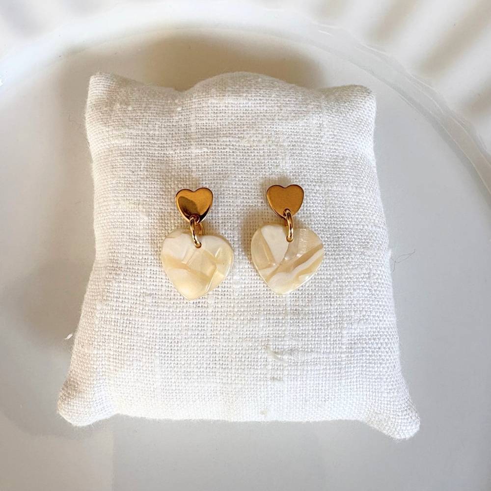 boucles d oreilles cœur beige marbré Assia posées sur coussin blanc