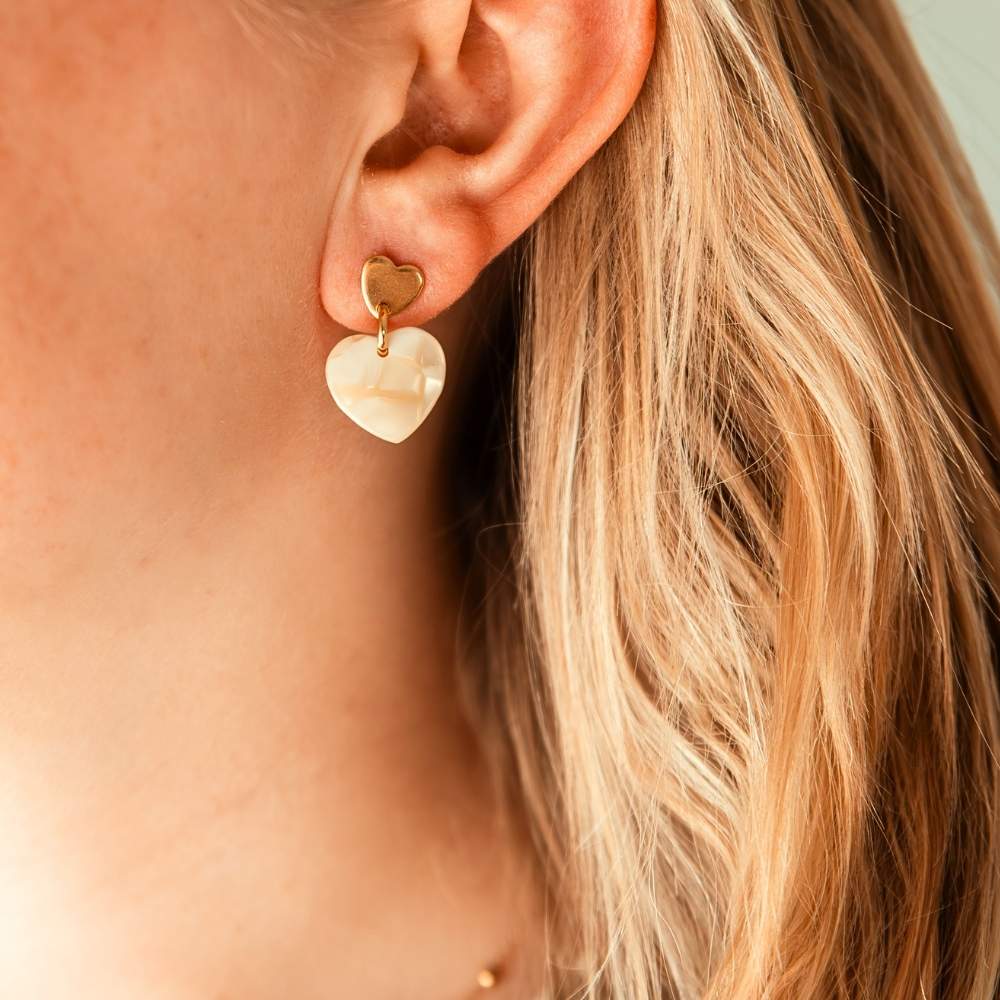 boucles d oreilles coeur beige Assia avec pendentif nacré portées sur oreille