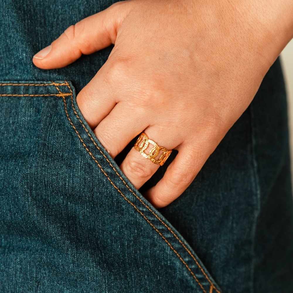 bague maillons Nelia portée a la main avec un jean en acier inoxydable doré