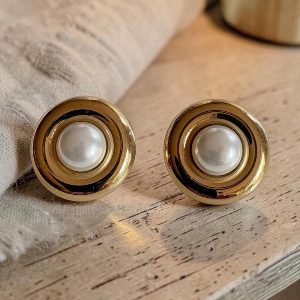 Boucles d’oreilles vintage Paulette dorées avec boule en résine nacrée sur table en bois