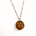 collier avec medaille frappee avec une balance symbolisant le signe astrologique expose fond blanc