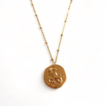 collier avec medaille frappee avec creature symbolisant le signe astrologique capricorne expose fond blanc