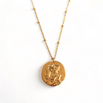 collier avec medaille frappee avec un motif symbolisant le signe astrologique verseau expose sur fond blanc