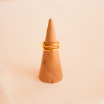 bague plaque or femme minimaliste double anneau dont un incurve exposee sur cone en bois marine