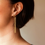 boucles d oreilles chaines pendantes dorees avec accroche forme anneau creux et motif noeud portees oreille gauche paloma