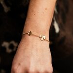 bracelet fleurs acier dore avec chaine ornee de deux fleurs texturees et porte sur bras gauche a la verticale heloise