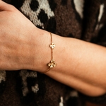 bracelet fleurs en acier inoxydable avec chaine fine doree et deux fleurs de tailles différentes porte sur poignet gauche heloise