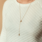 collier en y en acier inoxydable dore longue chaine et noeuds porte sur haut blanc sidonie