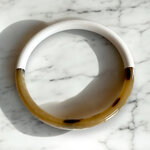 bracelet jonc en corne laquee blanc expose sur fond marbre swann