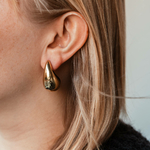 boucles d oreilles gouttes d eau en acier dore bombees portees oreille gauche amaya