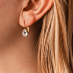 boucle oreille pendante avec cristal transparent format goutte et fermoir dormeuse en acier dore portee oreille gauche naelle