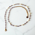 collier pierre amethyste lumineux en acier dore avec differentes perles alternees sur chaine et mis en valeur fond blanc jaia