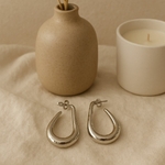 creoles argentees au design forme goutte epure et moderne en acier mises en valeur avec fond neutre decoratif anna