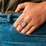 bague epaisse ovale ajustable au design creux et simple portee sur majeur gauche avec doigts dans la poche berenice